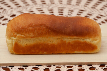 Delicious and traditional Brazilian homemade bread on wooden board. Front view. Background with crochet towel.