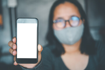 Asian woman wearing glasses and hygiene mask is lifted with blank white desktop copy space screen