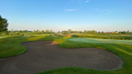 Naklejka premium sunrise on golf course golf green flag pole sand trap morning moon