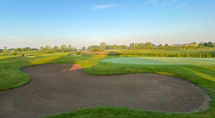 sunrise on golf course golf green flag pole sand trap morning moon