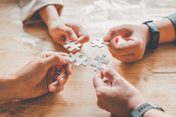 Business team handle a piece of white puzzles that are about to drop to get a complete worksheet - An attempt to succeed.