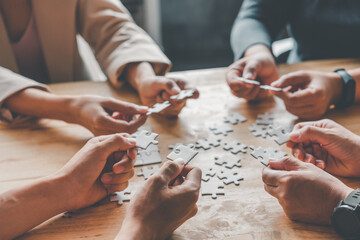 Business team handle a piece of white puzzles that are about to drop to get a complete worksheet - An attempt to succeed.