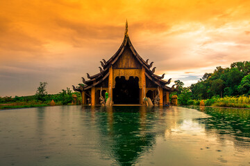 Naklejka premium The background of the Wat Pa Kham Charoen is a beautiful old church with a Buddhist statue and a tree-lined temple, with tourists and travelers always making merit in Udon Thani, Thailand.
