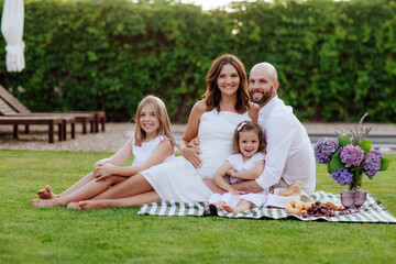 A beautiful family with two daughters and a pregnant mother on a picnic