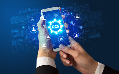 Female hand holding smartphone with RCS abbreviation, modern technology concept - obrazy, fototapety, plakaty