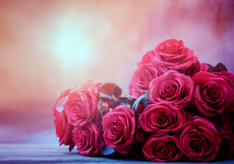 red roses bouquet on wood floor against colorful blur background