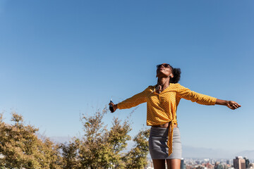 young beautiful black woman enjoying nature while listening to music and dancing