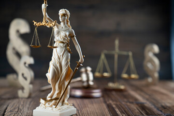 Law symbols composition. Themis statue, judge’s gavel and scale of justice on rustic wooden desk.
