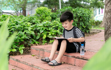 Naklejka premium Cute little boy Read a book in the park