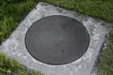 Fototapeta na wymiar Steel manhole cover in the grass