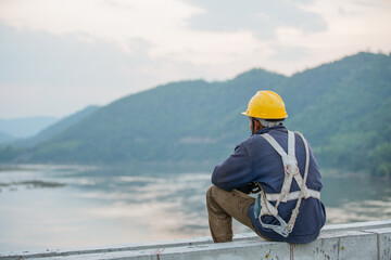Asian Worker resting after hard working, looking  view over Mekong river, carrying his safety suit on shoulder. 