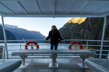 Asian woman looking at view with beautiful scenic of milford sound in fiordland national park new zealand.