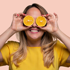 Happy and smiling young man playing with an orange cut in half and in front of his eyes. Photo on...