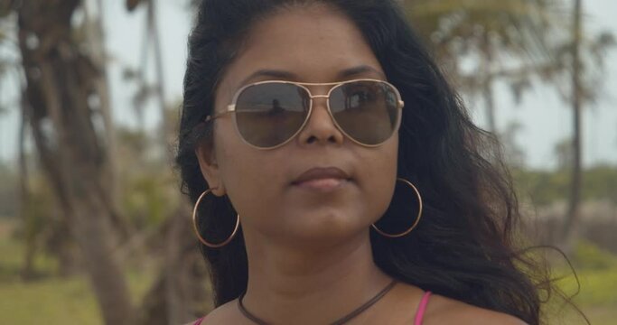 Pretty face model wearing sunglasses and hoop earing at this coastline Caribbean location