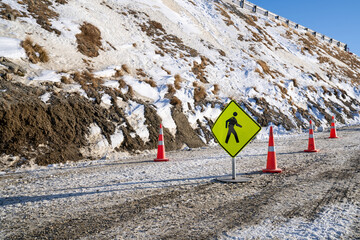 Coution sign board on snow road at the snow hill.