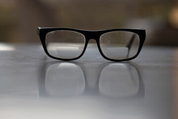 Old dirty black glasses on the desk.