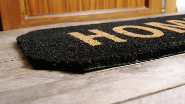 Man putting spare key under the door mat