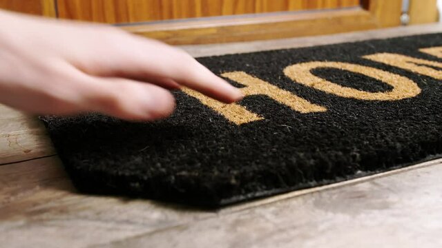 Man putting spare key under the door mat
