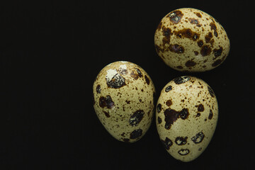 Fototapeta premium Quail eggs on a black background, close up.