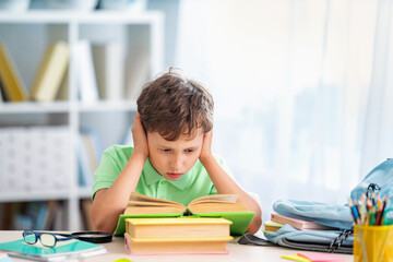 tired, frustrated schoolboy with a pile of school books and notebooks.