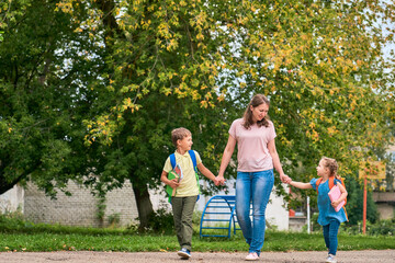 Woman and two children from back. mother accompanies the students along way.