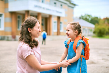 mother accompanies to school and supports her daughter morally, holding hands.