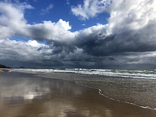 Australian beach with storm clouds and reflections in the sand, Mudjimba Beach, Queensland