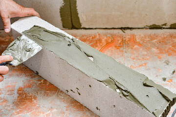 A worker applies adhesive mortar to a wall block in a private house. Foam masonry, repair and construction.