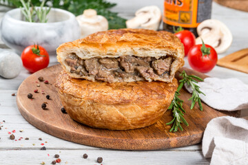 Oven cooked meat pie served on a round wooden board