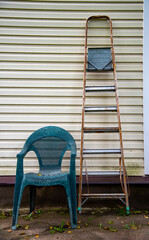 A stepladder and a plastic garden chair stand against the wall.