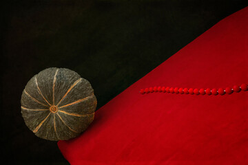 Still life "Rolling pumpkin" with a pumpkin on a red table and with red beads