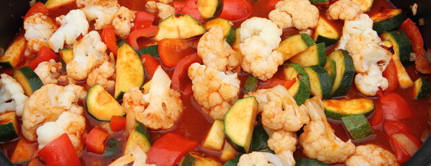 a pan with cauliflower, zucchini, peppers and tomato