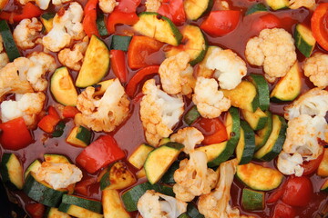 a pan with cauliflower, zucchini, peppers and tomato