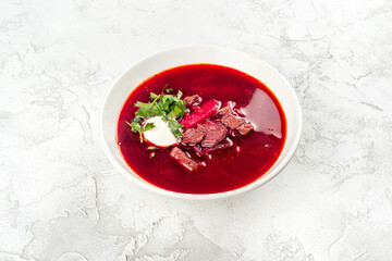 Borsch with sour cream, herbs and meat in a white, round plate
