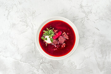 Borsch with sour cream, herbs and meat in a white, round plate