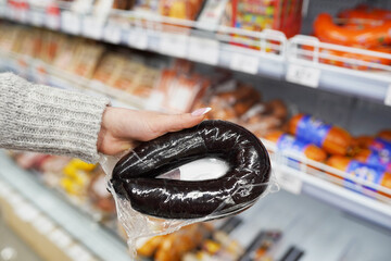 Female hand holding blood sausage, ukrainian national sausage, in the market
