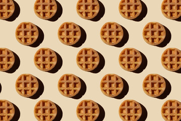 Soft round fried waffles on a beige background. Monochrome pattern with hard shadows.