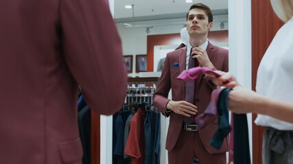 Young businessman looks at the mirror and trys on different ties