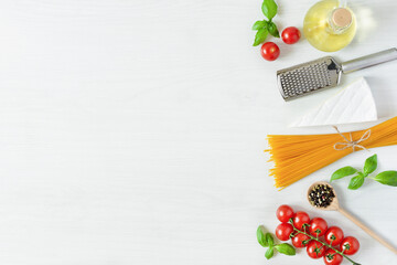 Italian pasta ingredients for cooking. Raw pasta, cheese, vegetables, spices and herbs top view on white wooden background.