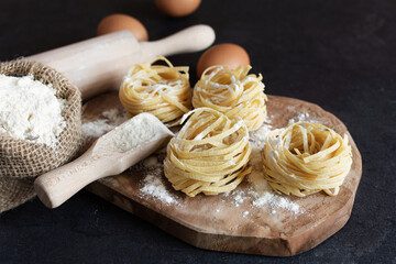 Fototapeta na wymiar Raw homemade fettuccine pasta on black background.