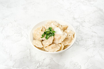 Dumplings with sour cream and herbs in a round, white plate