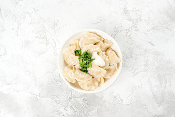 Dumplings with sour cream and herbs in a round, white plate