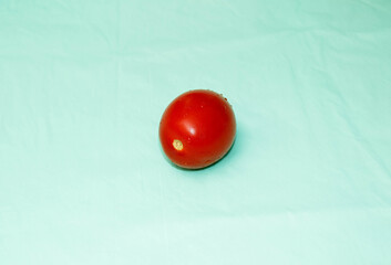 Red ripe tomato on a turquoise background close-up.