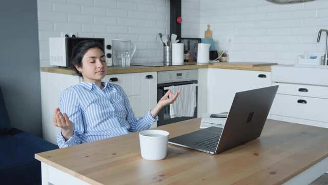 Young indian business woman worker relax sit at office desk finished laptop computer work put hands behind head feel satisfied with work well done stress relief peace of mind concept chill at work