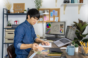 Asian men Architect or graphic designer designing a layout selection swatch samples for coloring...