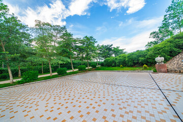 The tile floor of the outdoor park square is under the blue sky and white clouds.