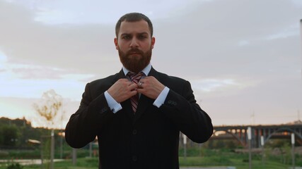 Attractive businessman is Correcting his suit and poring on camera outdoors