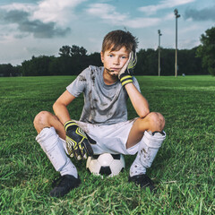 Muddy and tired young soccer boy sitting on ball after a game © 3Days2Go Media