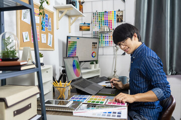Obraz premium Asian men Architect or graphic designer designing a layout selection swatch samples for coloring screen 