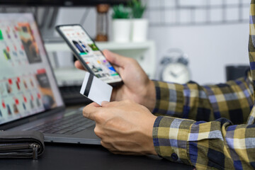 Asian man holding credit card to Online shopping with laptop computer and entering security code
